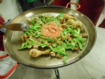 The meat is moved outward, and other ingredients are added to the pan at the center.